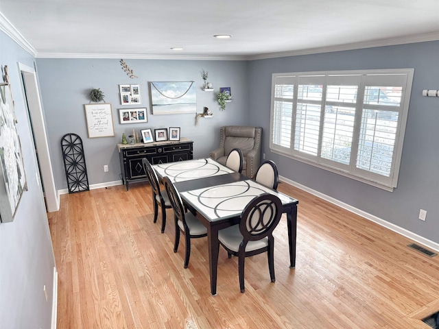 dining area featuring ornamental molding and light wood-type flooring