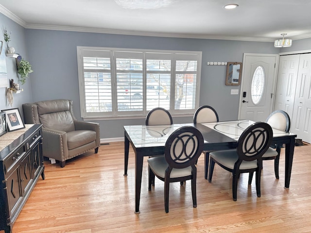 dining space featuring light hardwood / wood-style flooring and crown molding