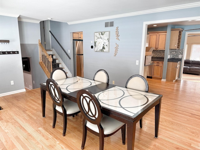 dining room with ornamental molding and light hardwood / wood-style flooring