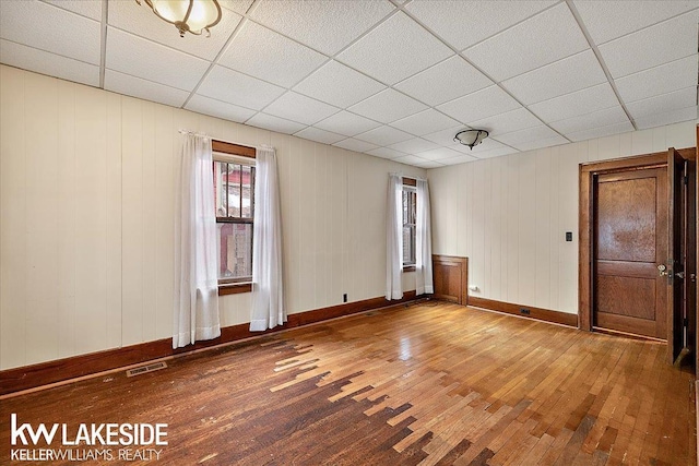 empty room with wood-type flooring and a drop ceiling