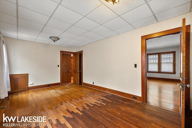 empty room with hardwood / wood-style floors and a drop ceiling