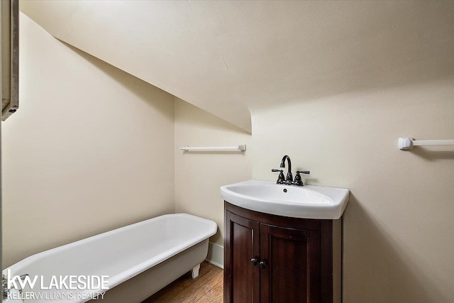 bathroom featuring a tub, lofted ceiling, hardwood / wood-style floors, and vanity