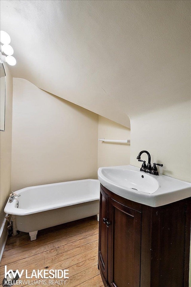 bathroom featuring a textured ceiling, vanity, a bathtub, and wood-type flooring