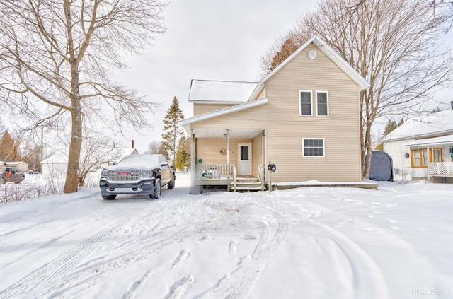 snow covered rear of property with covered porch