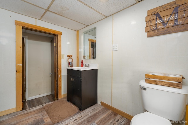 bathroom featuring a paneled ceiling, toilet, hardwood / wood-style flooring, and vanity