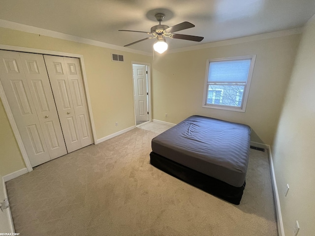 bedroom featuring ceiling fan, crown molding, light carpet, and a closet