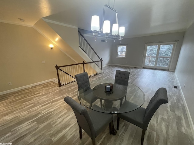 dining room featuring hardwood / wood-style flooring, ornamental molding, and an inviting chandelier