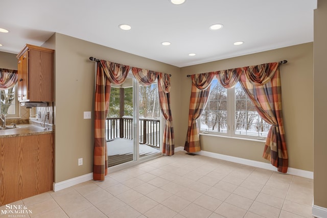 unfurnished dining area featuring light tile patterned flooring, a wealth of natural light, and sink