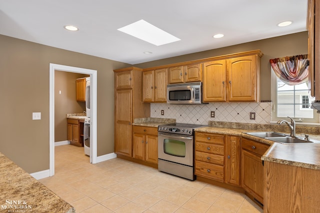 kitchen with decorative backsplash, stainless steel appliances, light tile patterned floors, and sink