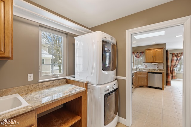 laundry room with sink, cabinets, stacked washer and dryer, and light tile patterned floors