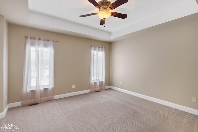 unfurnished room with a tray ceiling, light carpet, and ceiling fan