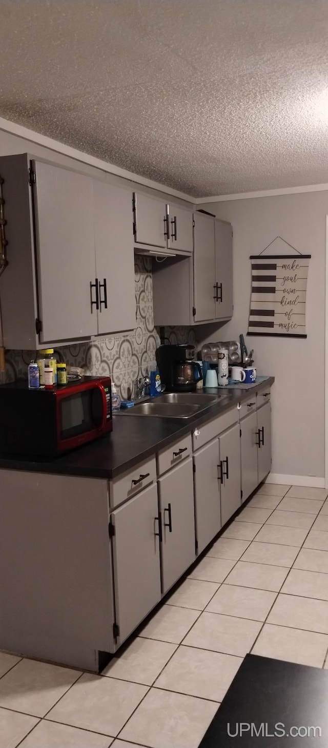 kitchen featuring light tile patterned floors, sink, crown molding, and a textured ceiling