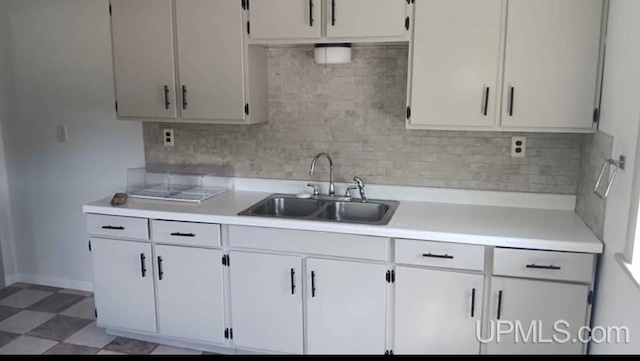 kitchen featuring sink, backsplash, and white cabinets