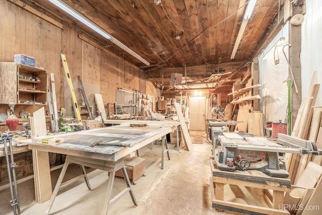 miscellaneous room with concrete flooring, wooden ceiling, a workshop area, and wooden walls