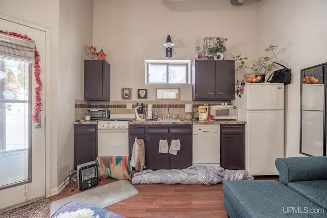 kitchen featuring sink, backsplash, white appliances, and hardwood / wood-style floors