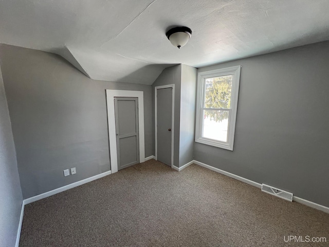 additional living space featuring carpet flooring and vaulted ceiling