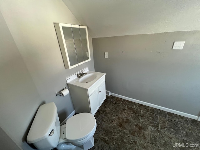 bathroom with toilet, vanity, and lofted ceiling