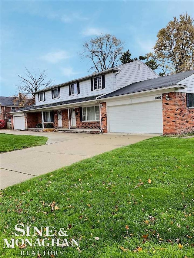 traditional-style house with driveway, an attached garage, a front lawn, and brick siding