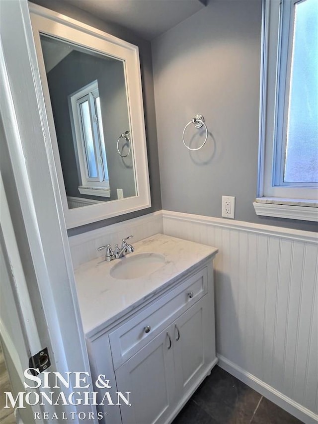 bathroom featuring tile patterned flooring, wainscoting, and vanity