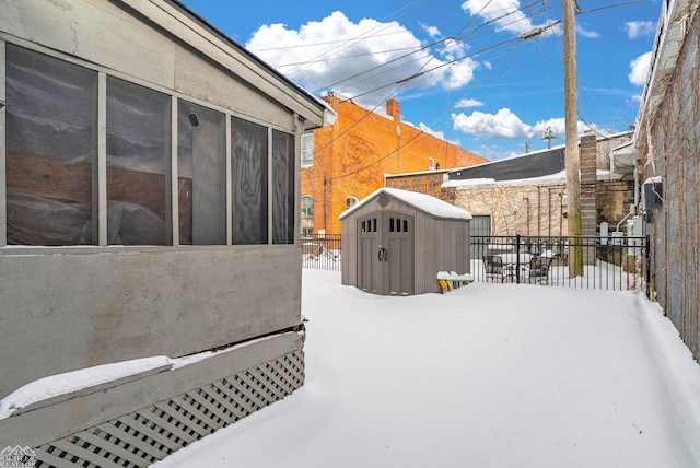 snow covered patio featuring a storage shed