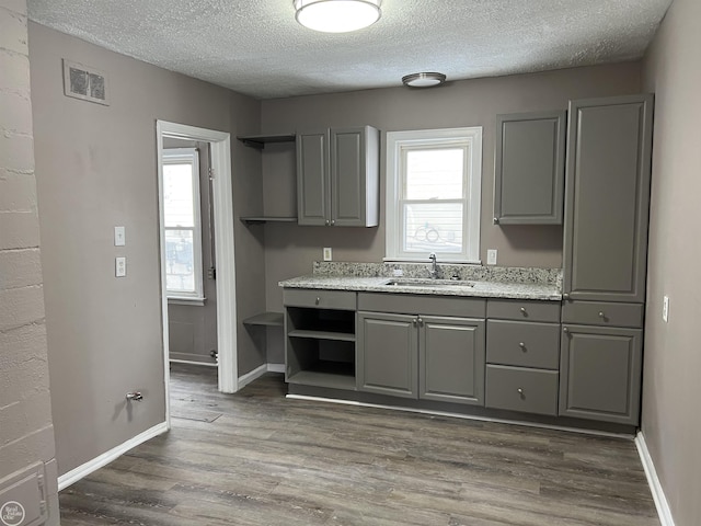 kitchen featuring visible vents, dark wood-type flooring, gray cabinets, open shelves, and a sink