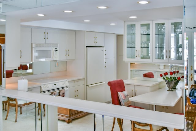 kitchen featuring a breakfast bar area, white appliances, and white cabinets