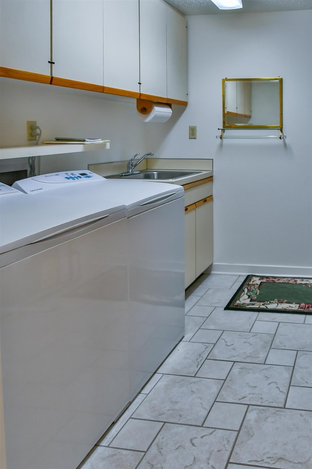 laundry room with cabinets, washing machine and dryer, and sink