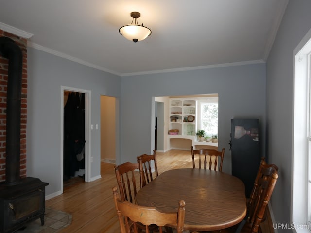 dining room with a wood stove, light hardwood / wood-style flooring, and ornamental molding