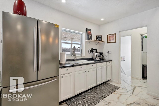 kitchen with white cabinets, dark countertops, freestanding refrigerator, marble finish floor, and open shelves