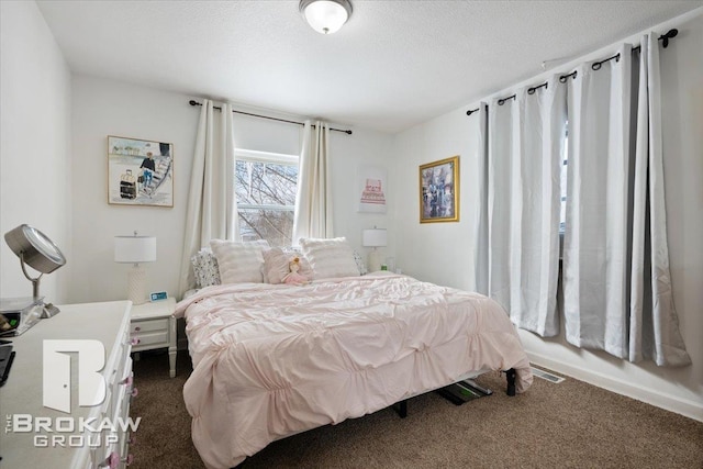 bedroom featuring dark colored carpet, visible vents, and a textured ceiling