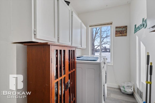 washroom with cabinet space, light wood finished floors, visible vents, baseboards, and separate washer and dryer