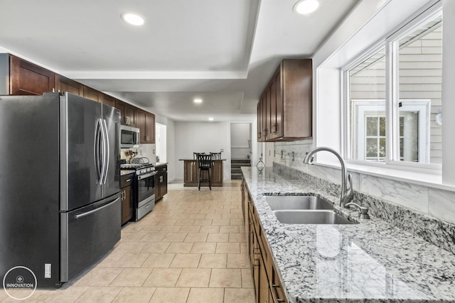 kitchen with light tile patterned floors, sink, stainless steel appliances, light stone countertops, and tasteful backsplash