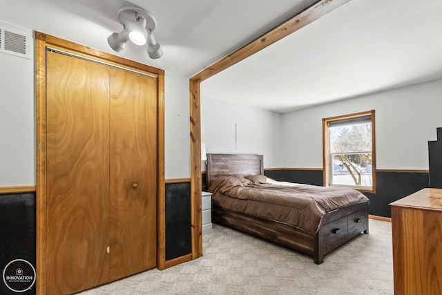 bedroom with a closet, light colored carpet, and beam ceiling