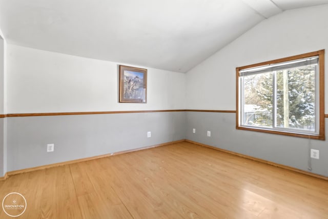 empty room featuring light hardwood / wood-style floors and vaulted ceiling