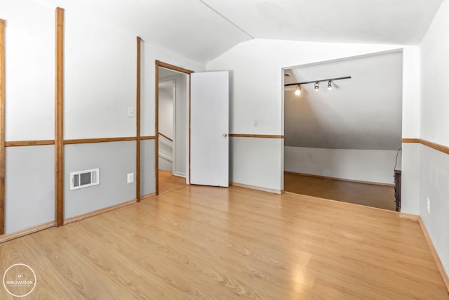 unfurnished room with light hardwood / wood-style floors and lofted ceiling