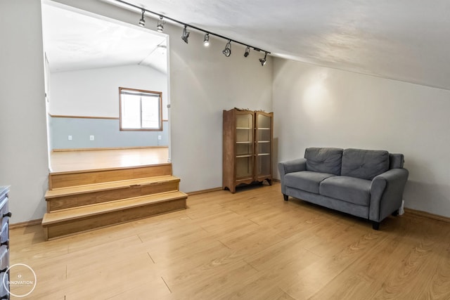 living area featuring light hardwood / wood-style floors, lofted ceiling, and rail lighting