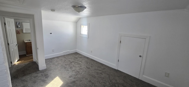 unfurnished bedroom featuring a textured ceiling, lofted ceiling, and carpet flooring