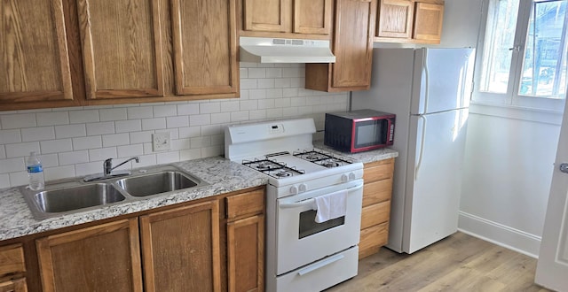 kitchen with white appliances, sink, light hardwood / wood-style floors, light stone countertops, and tasteful backsplash