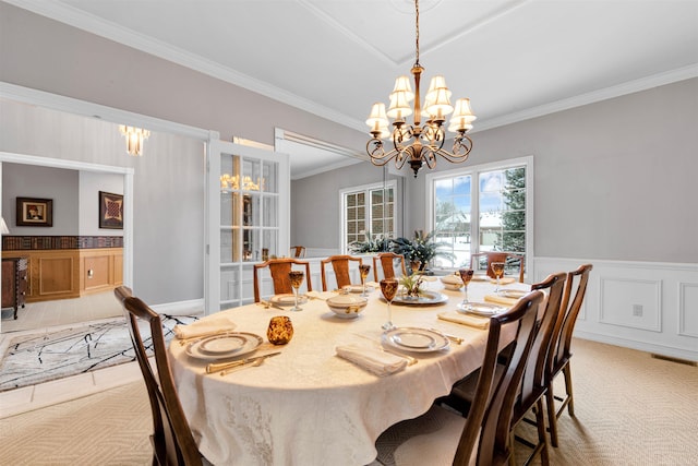 dining room with ornamental molding, light carpet, and a chandelier