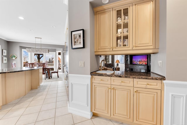 kitchen with light tile patterned floors, sink, hanging light fixtures, and dark stone countertops