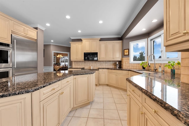 kitchen with tasteful backsplash, stainless steel appliances, light tile patterned floors, sink, and dark stone countertops