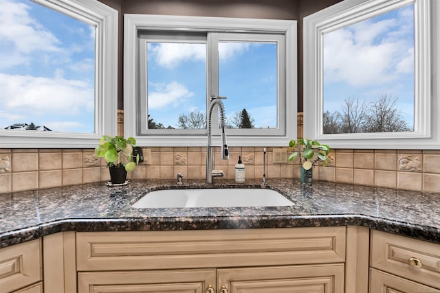 kitchen featuring sink, cream cabinetry, and dark stone countertops