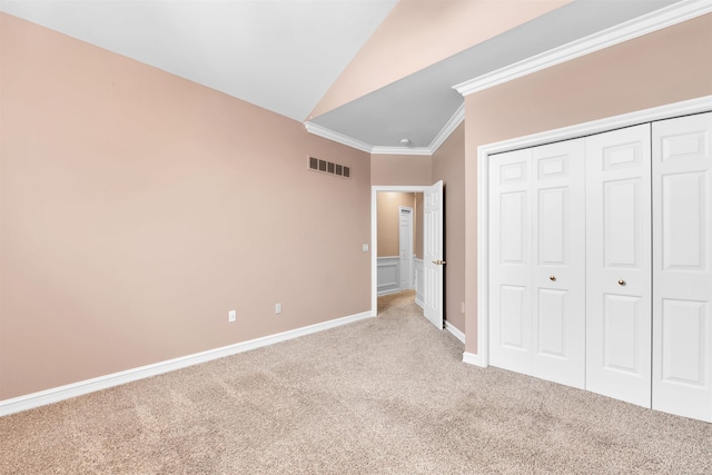 unfurnished bedroom with light colored carpet, lofted ceiling, a closet, and ornamental molding