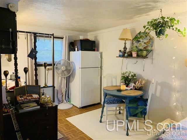 kitchen with a textured ceiling, white fridge, and parquet floors