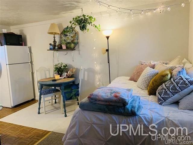 bedroom with parquet floors and white refrigerator