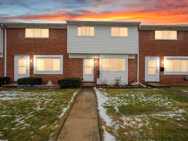 view of property featuring brick siding and a yard