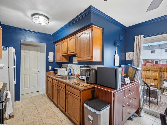 kitchen featuring brown cabinetry, crown molding, a sink, and white appliances