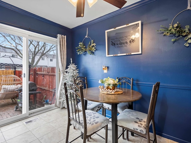 dining room with visible vents, a ceiling fan, light tile patterned floors, and crown molding