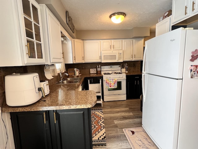 kitchen with white cabinetry, glass insert cabinets, a sink, and white appliances