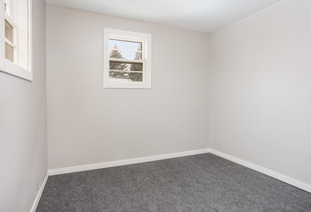 unfurnished room with baseboards and dark colored carpet